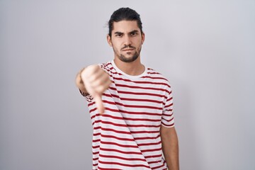 Fototapeta premium Hispanic man with long hair standing over isolated background looking unhappy and angry showing rejection and negative with thumbs down gesture. bad expression.