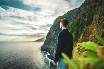 Man in shirt looking at waterfall flowing into the sea in atmospheric morning atmosphere. Viewpoint...
