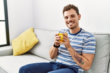 Young hispanic man smiling confident drinking coffee at home