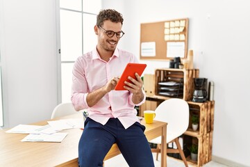 Young hispanic man smiling confident using touchpad at office