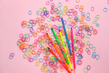 Colorful rubber bands and pencils on pink background