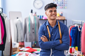Young hispanic man tailor smiling confident standing with arms crossed gesture at clothing factory