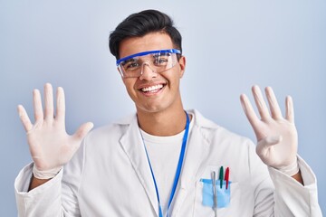 Hispanic man working as scientist showing and pointing up with fingers number nine while smiling...