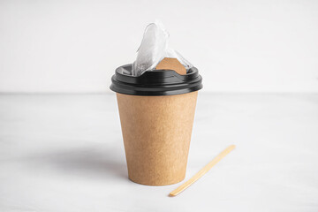 Paper cup, stick and tea bag on light background