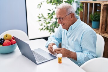 Senior grey-haired man having telemedicine sitting on table at home