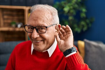 Senior man smiling confident using deafness hearing aid at home - obrazy, fototapety, plakaty