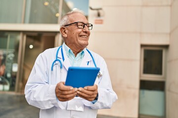 Senior man wearing doctor uniform using touchpad at street