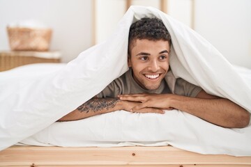 African american man lying on bed covering with bedsheet at bedroom