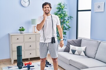 Handsome latin man wearing sportswear at home touching mouth with hand with painful expression because of toothache or dental illness on teeth. dentist