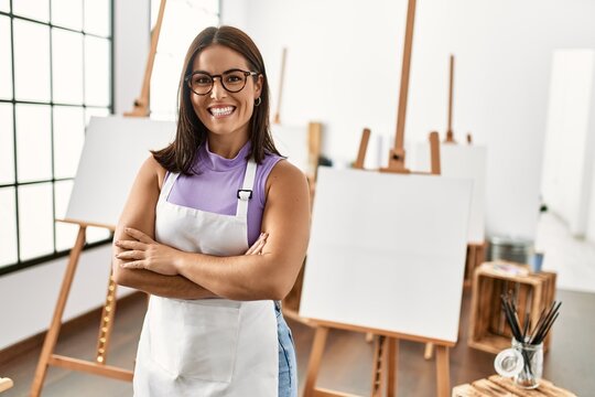 Young beautiful hispanic woman artist smiling confident standing with arms crossed gesture at art studio