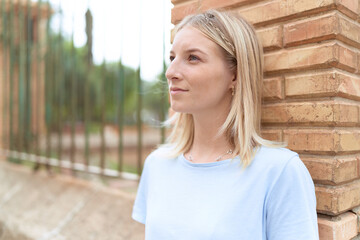 Fototapeta premium Young blonde woman looking to the side with serious expression at street