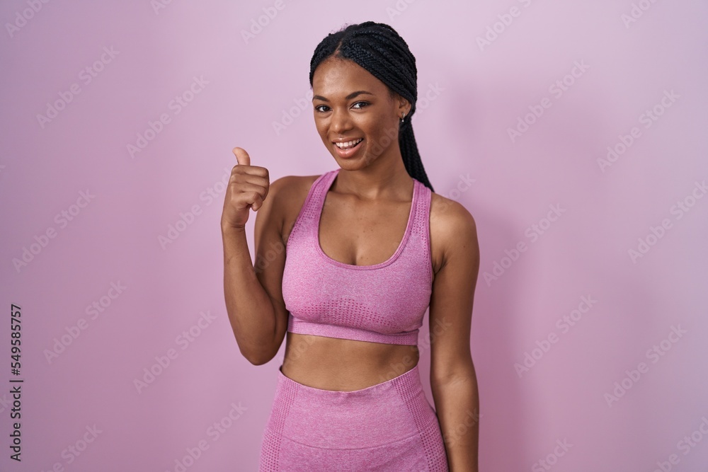 Poster african american woman with braids wearing sportswear over pink background doing happy thumbs up ges