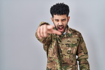 Arab man wearing camouflage army uniform pointing displeased and frustrated to the camera, angry...