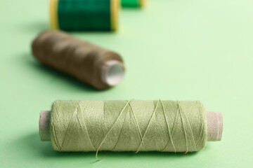 Sewing thread spools on green background, closeup