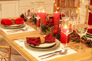 Christmas table setting with burning candles, fir cones and rowan in kitchen, closeup
