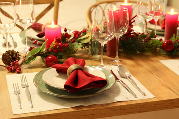Christmas table setting with burning candles, fir cones and rowan in kitchen, closeup