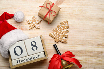 Obraz premium Cube calendar with date 8 DECEMBER, Santa hat, Christmas bell, cookies and gifts on wooden background