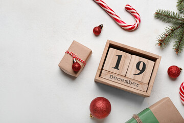 Cube calendar with date 19 DECEMBER, Christmas decor and gifts on light background - obrazy, fototapety, plakaty