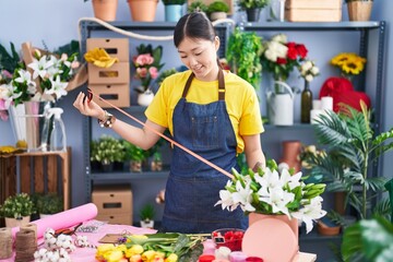 Chinese woman florist smiling confident holding lace at florist shop