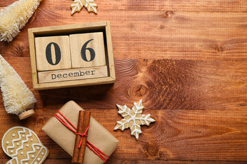 Cube calendar with date 6 DECEMBER, Christmas trees, cookies and gift on wooden background