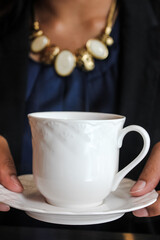 Obraz na płótnie Canvas a woman holding a white ceramic cup saucer 