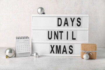 Board with text DAYS UNTIL XMAS, calendar, Christmas balls and gift on white background
