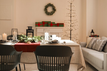 Christmas table setting with wreath and burning candles in dining room