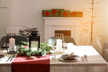 Christmas table setting with wreath and burning candles in dining room