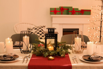 Christmas table setting with wreath and burning candles in dining room
