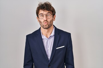 Hispanic business man wearing glasses making fish face with lips, crazy and comical gesture. funny expression.