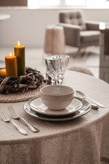 Christmas table setting with burning candles and wreath in kitchen, closeup