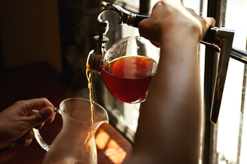 Barista pouring coffee from vacuum maker into glass jug in cafe, closeup