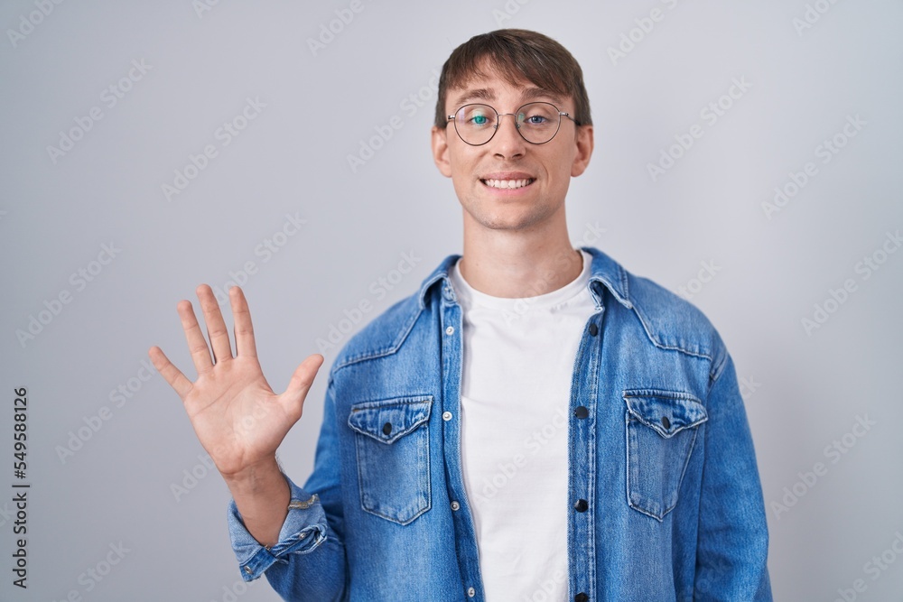 Poster caucasian blond man standing wearing glasses showing and pointing up with fingers number five while 