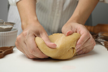 Woman kneading dough for cookies at white table, closeup