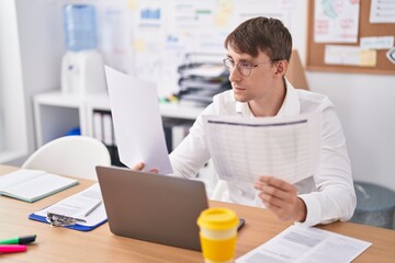 Young caucasian man business worker using laptop reading document at office