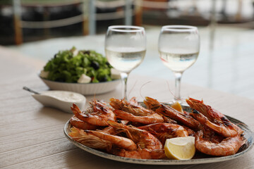 Plate of delicious cooked shrimps served with lemon and wine at table outdoors