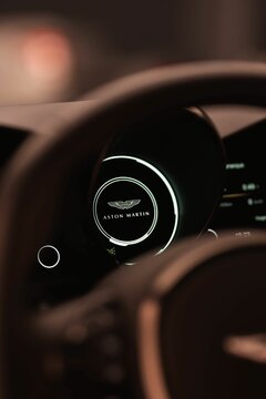 Vertical shot of an Aston Martin Vantage digital gauge cluster with the Aston Martin logo on it
