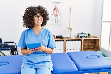 Young middle east woman wearing physio therapist uniform using touchpad at clinic