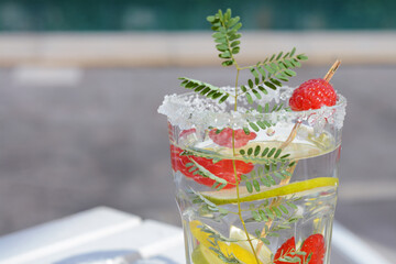 Delicious refreshing lemonade with raspberries outdoors, closeup. Space for text