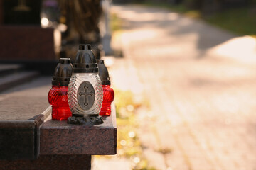 Grave lanterns on granite surface in cemetery, space for text