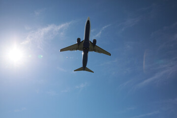 Modern white airplane flying in sky, bottom view