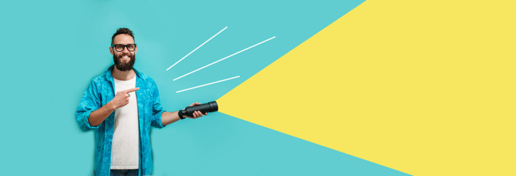 Young bearded hipster man holding a flashlight. Your text here. Discounts, sales, seasonal sales. Colorful summer concept. Modern creative artwork.