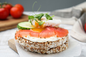 Crunchy buckwheat cakes with salmon, poached egg and cucumber slices served on board, closeup