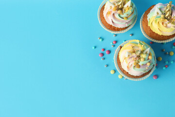 Obraz na płótnie Canvas Cute sweet unicorn cupcakes on light blue background, flat lay. Space for text