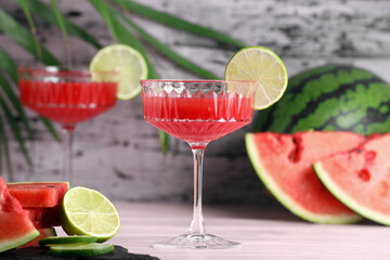 Cocktail glass of delicious fresh watermelon juice with lime on light wooden table
