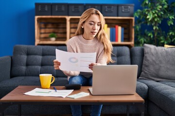Fototapeta premium Young woman sitting on sofa accounting at home