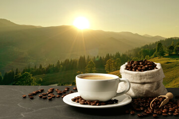 Cup of aromatic hot coffee on black table and beautiful view of mountain landscape. Space for text