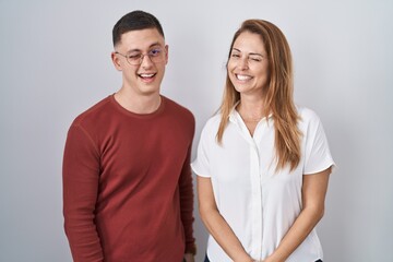 Fototapeta premium Mother and son standing together over isolated background winking looking at the camera with sexy expression, cheerful and happy face.
