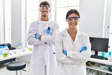 Man and woman partners wearing scientist uniform standing with arms crossed gesture at laboratory