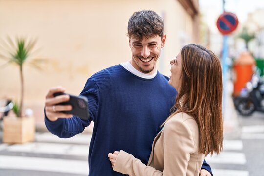 Mand and woman couple hugging each other make selfie by smartphone at street